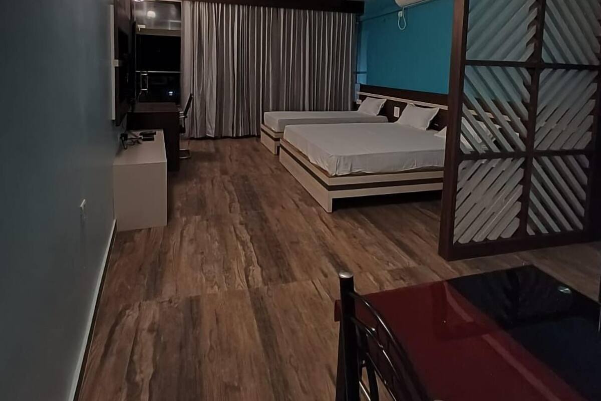Una habitación de hotel moderna con suelo de madera, una cama con cabecera, un escritorio y una silla.