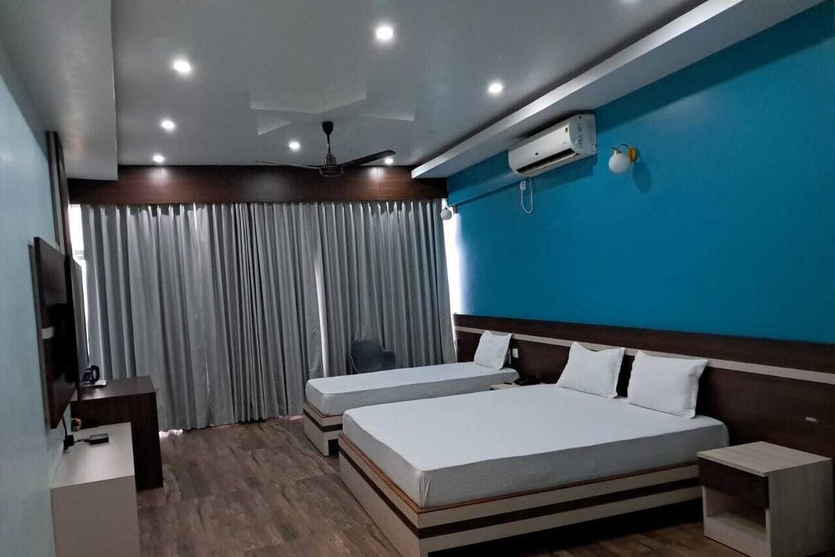 Habitación de hotel con dos camas, un escritorio, una silla, un televisor y un ventilador de techo.