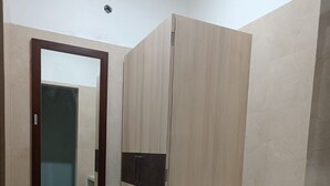 A room with a wardrobe, a mirror, and a small shelf. - River King City Palace (Guwahati)
