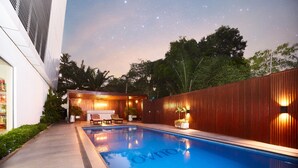 Ein Pool mit Holzterrasse, eine Lounge mit Sitzgelegenheiten und Blick auf den Nachthimmel.