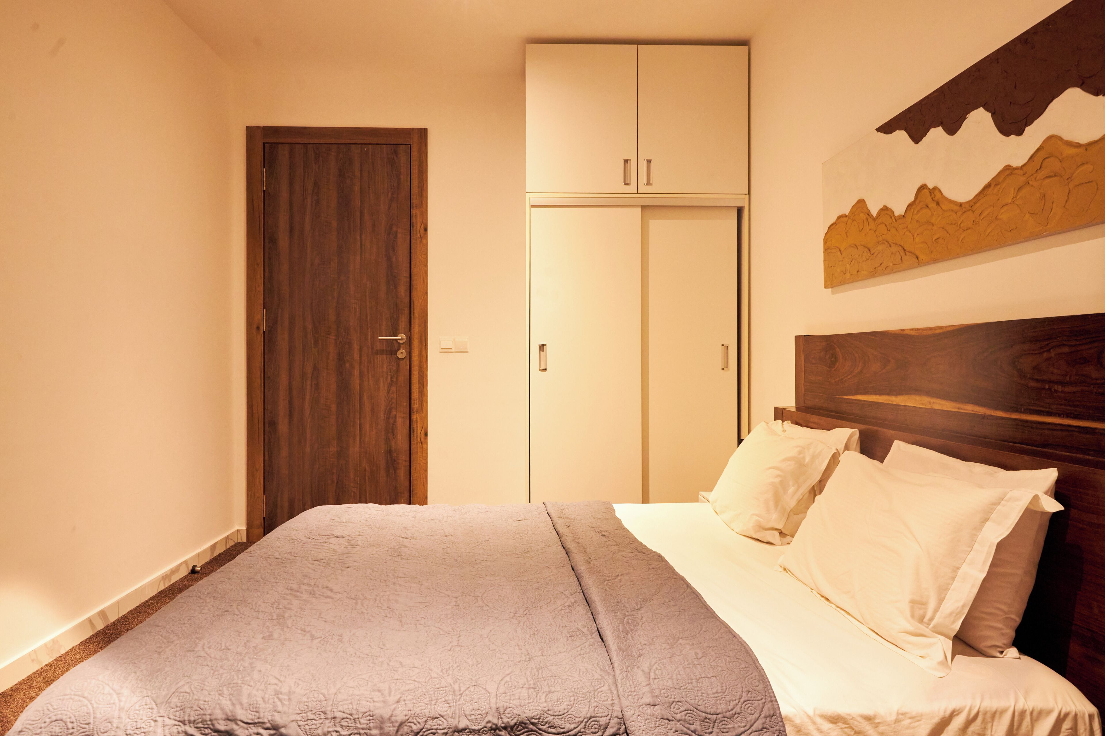 A bedroom with a bed, a wardrobe, and a painting on the wall.