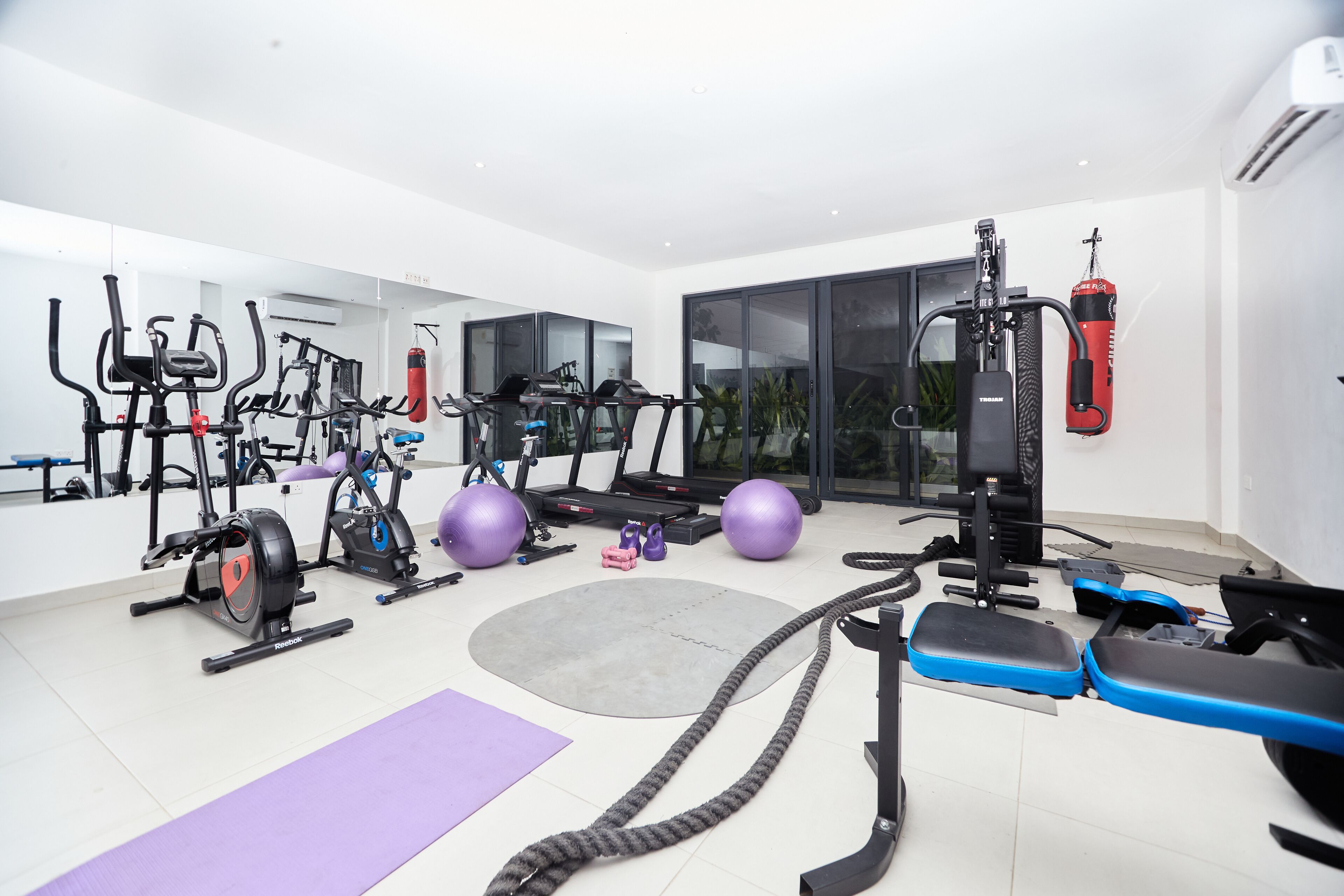 A modern home gym with various exercise equipment, including treadmills, stationary bikes, and free weights.