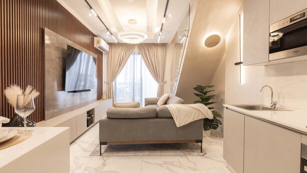 Eine moderne Küche mit Einbauofen, Spüle und Essbereich mit Sofa und Fernseher.