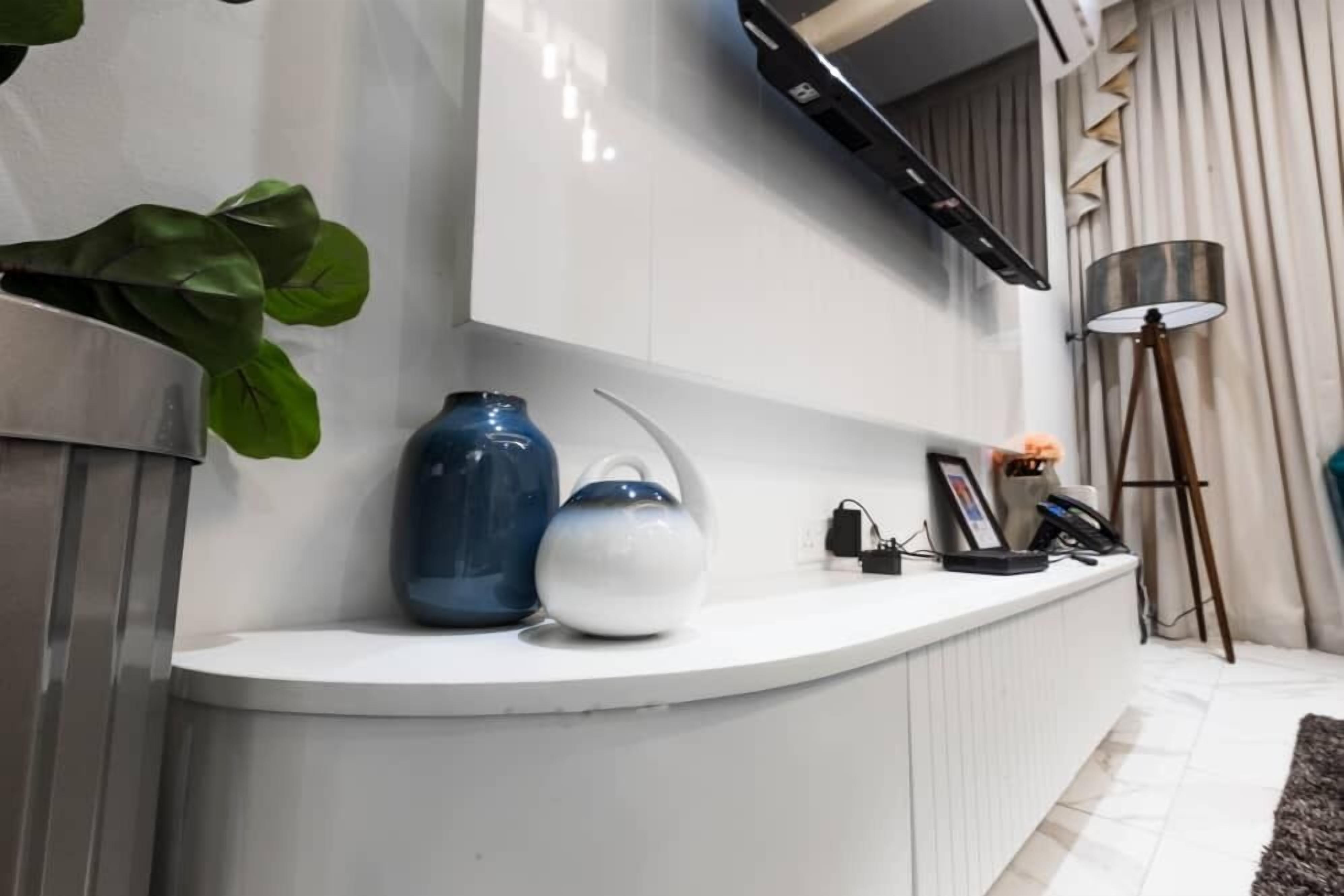 A modern reception desk with a white countertop, a blue vase, a white vase, and a small plant.