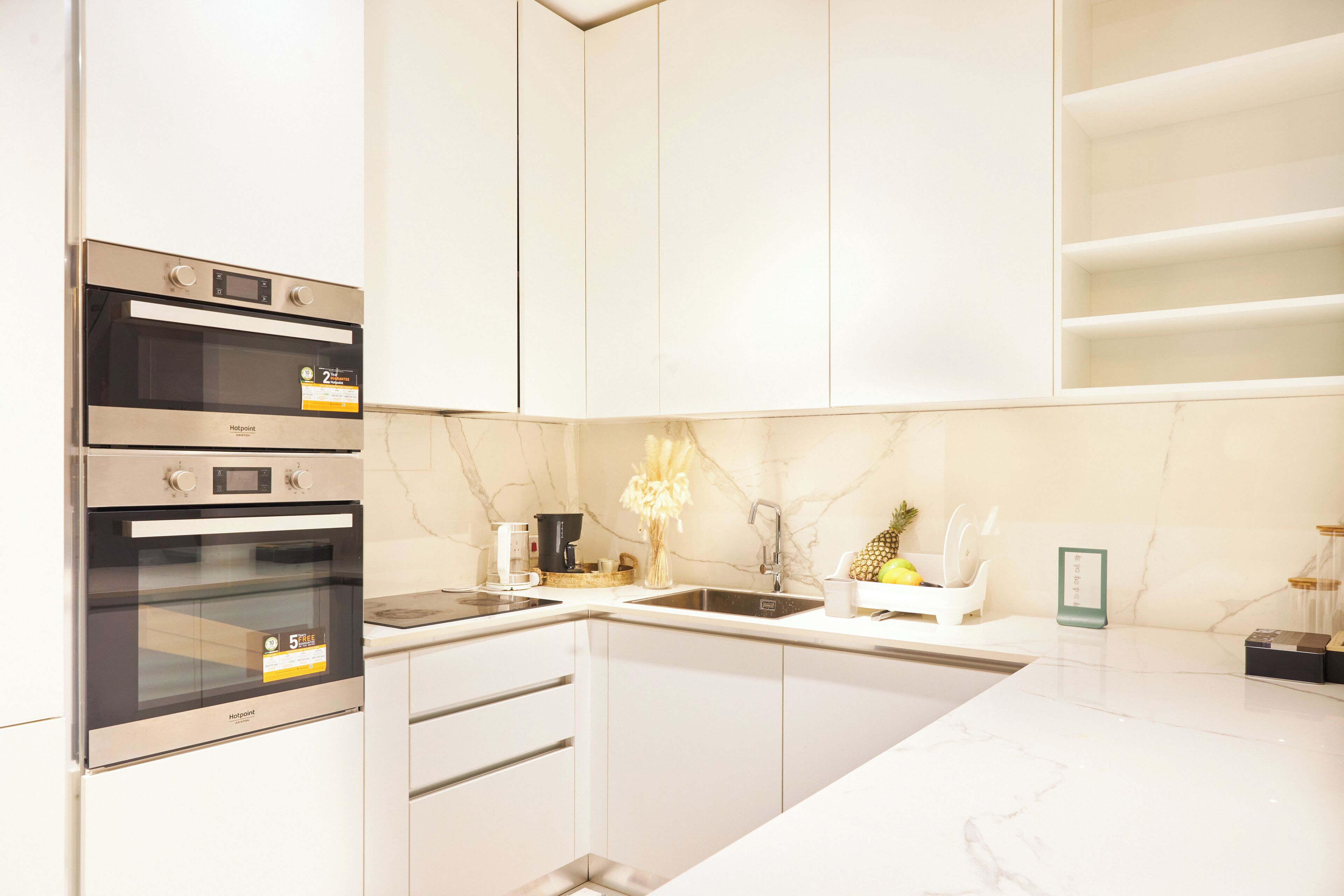 Una cocina moderna con hornos empotrados, un lavamanos y una encimera de mármol.