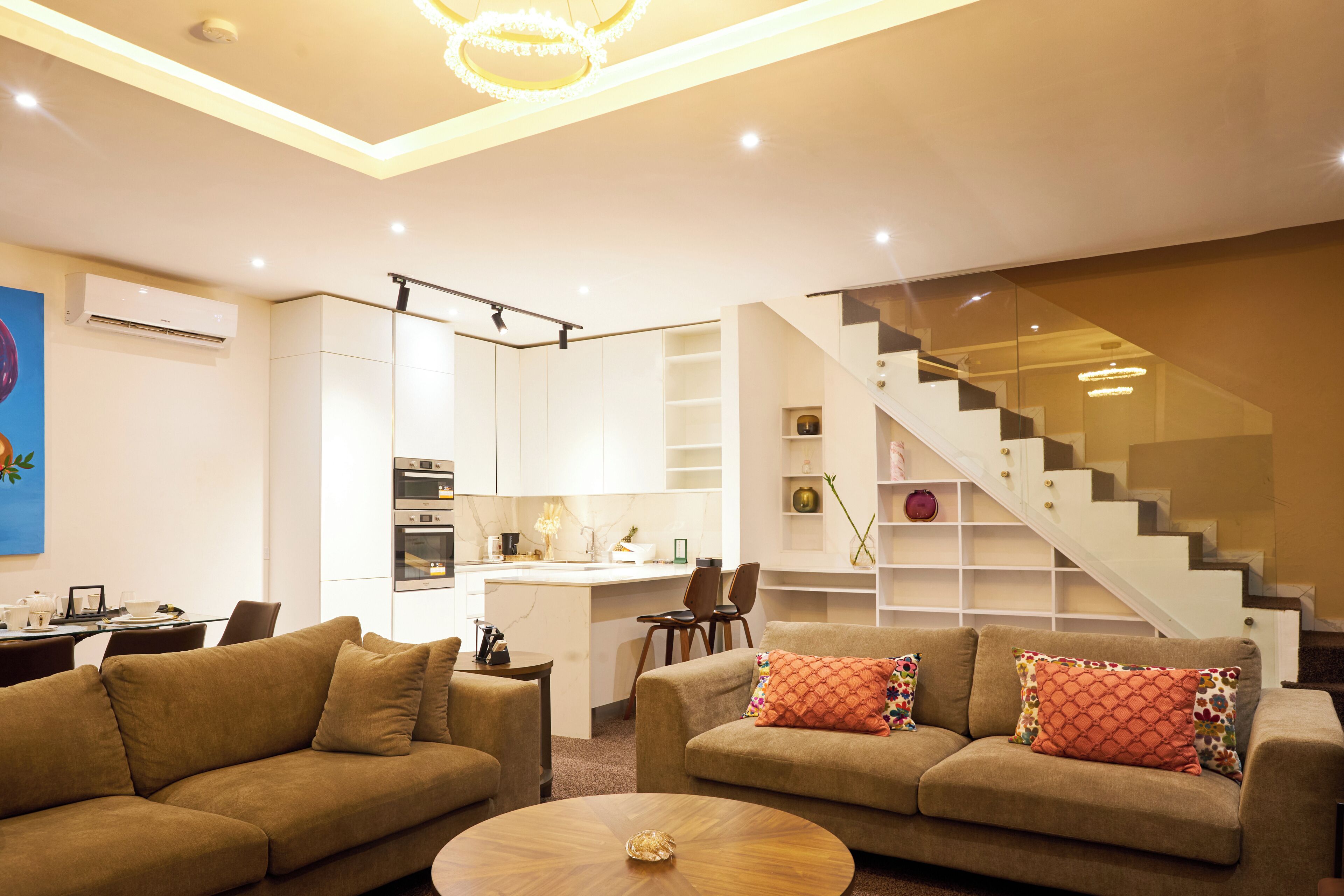 A modern living room with a sofa, coffee table, and a staircase leading to an upper level.