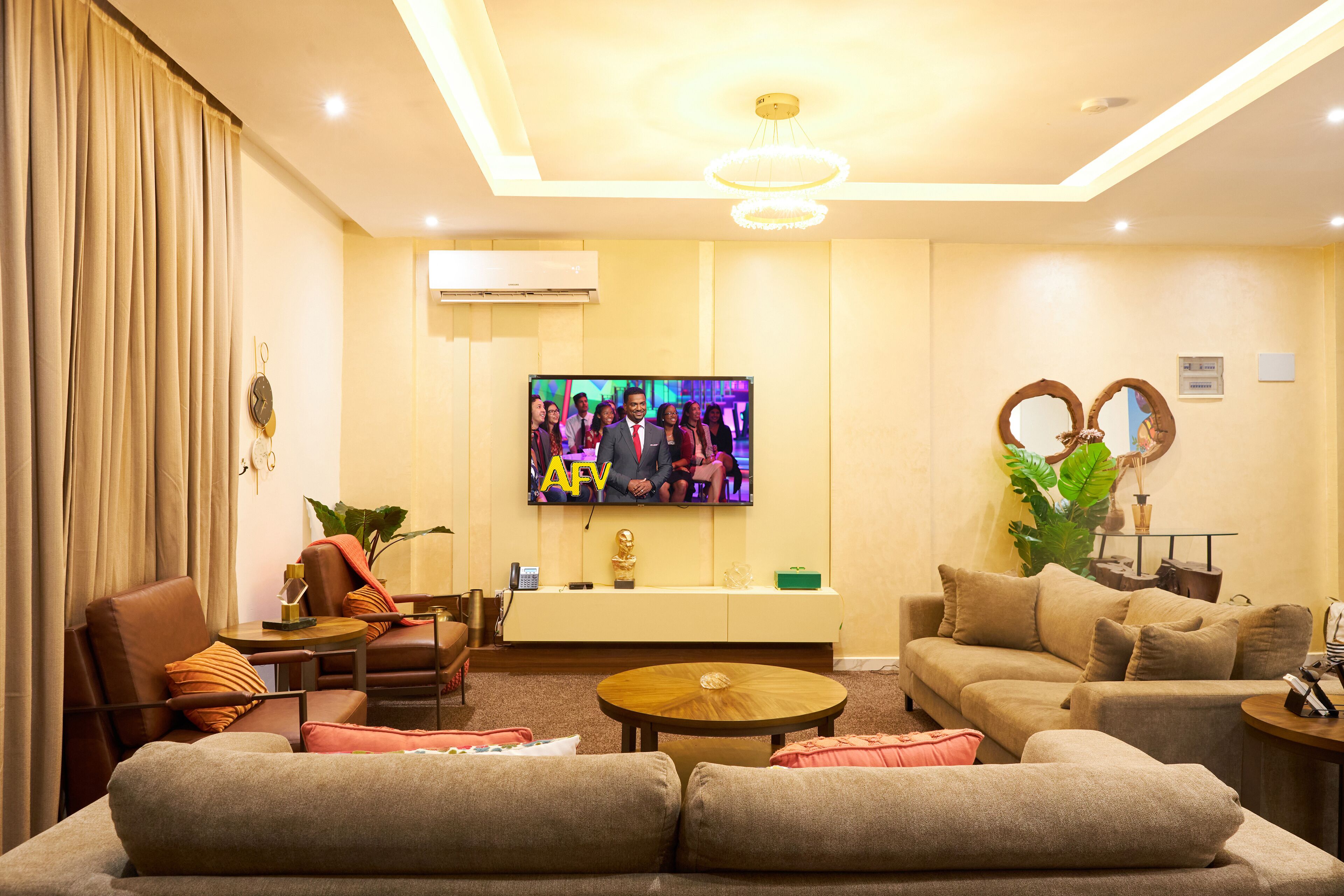 A modern living room with a sofa, armchairs, a coffee table, and a TV mounted on the wall.