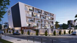 Ein modernes, mehrstöckiges Hotel mit auffälligem Nummernschild, Balkonen mit Bepflanzung und einer gut beleuchteten Fassade.