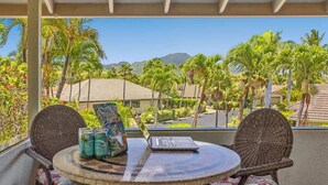 A balcony with wicker chairs, a round table, and a laptop.