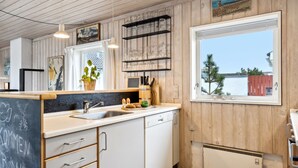 A modern kitchen with wooden paneling, a large window with a view of the sea, and a chalkboard with writing. - "Eljene" - 700m from the sea by Interhome (Pandrup)