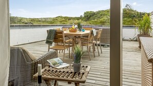 A wooden deck with a table and chairs, overlooking a body of water and greenery. - "Eljene" - 700m from the sea by Interhome (Pandrup)