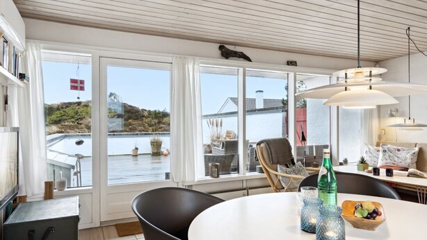 A modern dining area with a round table, black chairs, and a view of the sea through large windows. - "Eljene" - 700m from the sea by Interhome (Pandrup)