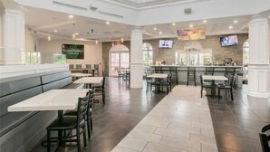 Un restaurante espacioso con techos altos, varias zonas de estar que incluyen cabinas y mesas, una zona de bar y una cocina a la vista.
