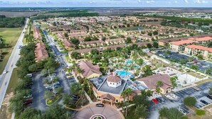 An aerial view of a residential area with a central building featuring a swimming pool, surrounded by houses and greenery. - Mario Kart Mayhem at Regal Palms Resort | Sage Vacations (Davenport)