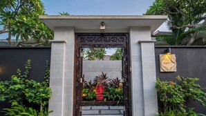 A traditional gate with intricate carvings, a small statue, and potted plants on either side. - Villa Eleni - Your Private Oasis in Seminyak - A Hosted Luxury Boutique Villa (Seminyak)