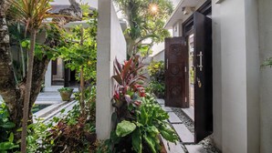 A narrow pathway flanked by lush greenery and a traditional wooden door. - Villa Eleni - Your Private Oasis in Seminyak - A Hosted Luxury Boutique Villa (Seminyak)