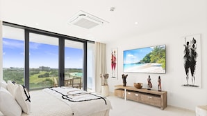 A bedroom with a large bed, a TV, and artwork on the wall. - b703 (Cupecoy)