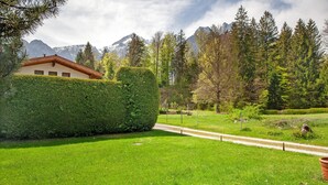 A well-maintained lawn, a pathway, and a building with a red roof. - Holiday home 'Grashäusl' with mountain views and private terrace (Grainau)