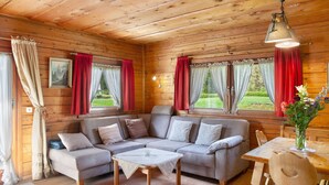 A cozy cabin interior with a sectional sofa, a wooden dining table, and a hanging light fixture. - Holiday home 'Grashäusl' with mountain views and private terrace (Grainau)