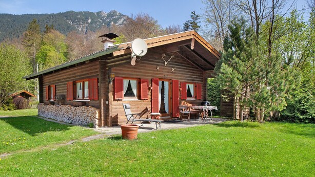 A rustic log cabin with a patio, outdoor seating, and a scenic mountain backdrop. - Holiday home 'Grashäusl' with mountain views and private terrace (Grainau)