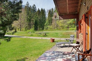 Une cabane en bois dotée d’un porche couvert, de meubles d’extérieur et offrant une vue sur une zone boisée.