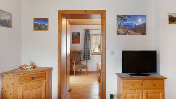 Een kamer met een bed, houten kasten, een televisie en ingelijste foto's aan de muur.