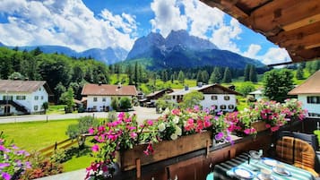 Een bergdorp met traditionele huizen, een houten balkon met bloemen en uitzicht op de bergen.