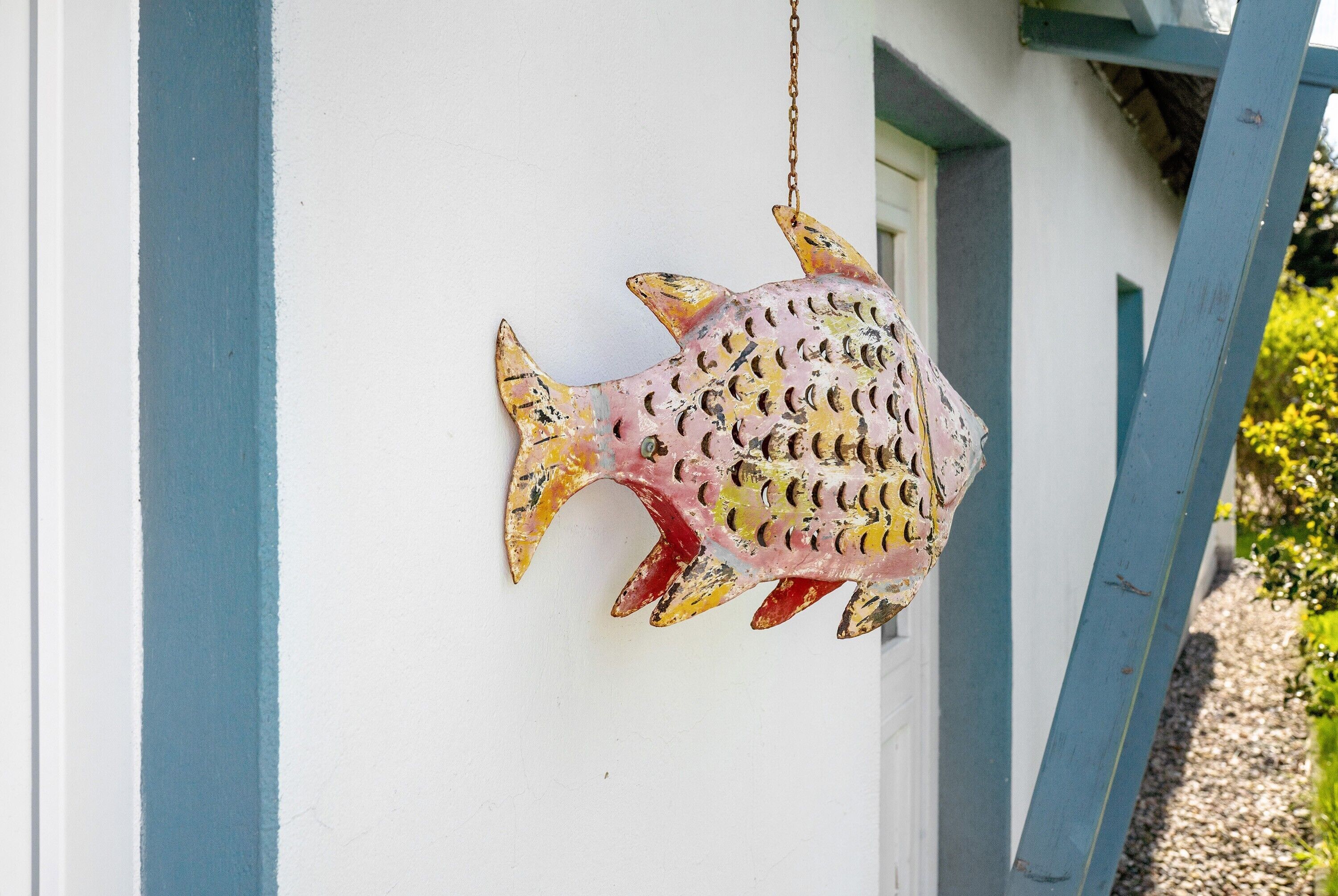 A fish-shaped decoration hanging on a white wall with blue trim.