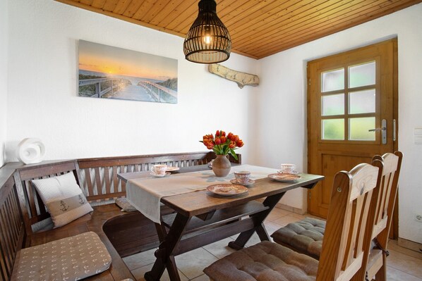 A dining area with a wooden table, benches, a vase with flowers, and a painting on the wall. - Holiday Apartment 'Ferienhaus Struve' with Private Garden (Trent)