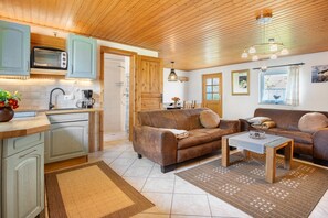 A cozy living area with a sofa, coffee table, and a kitchen with a microwave. - Holiday Apartment 'Ferienhaus Struve' with Private Garden (Trent)