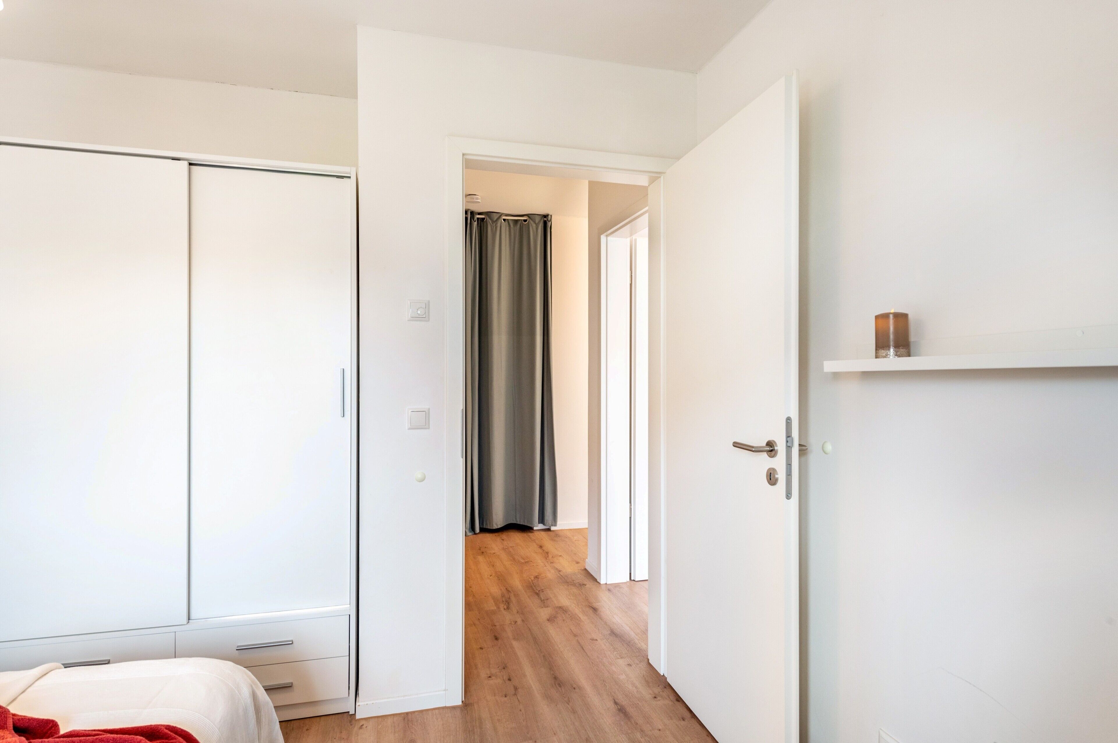 Ein Schlafzimmer mit Kleiderschrank, einem Bett und einem Flur, der zu einem Badezimmer führt.