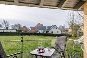 A balcony with a table, two glasses, and a pair of glasses on a tray.