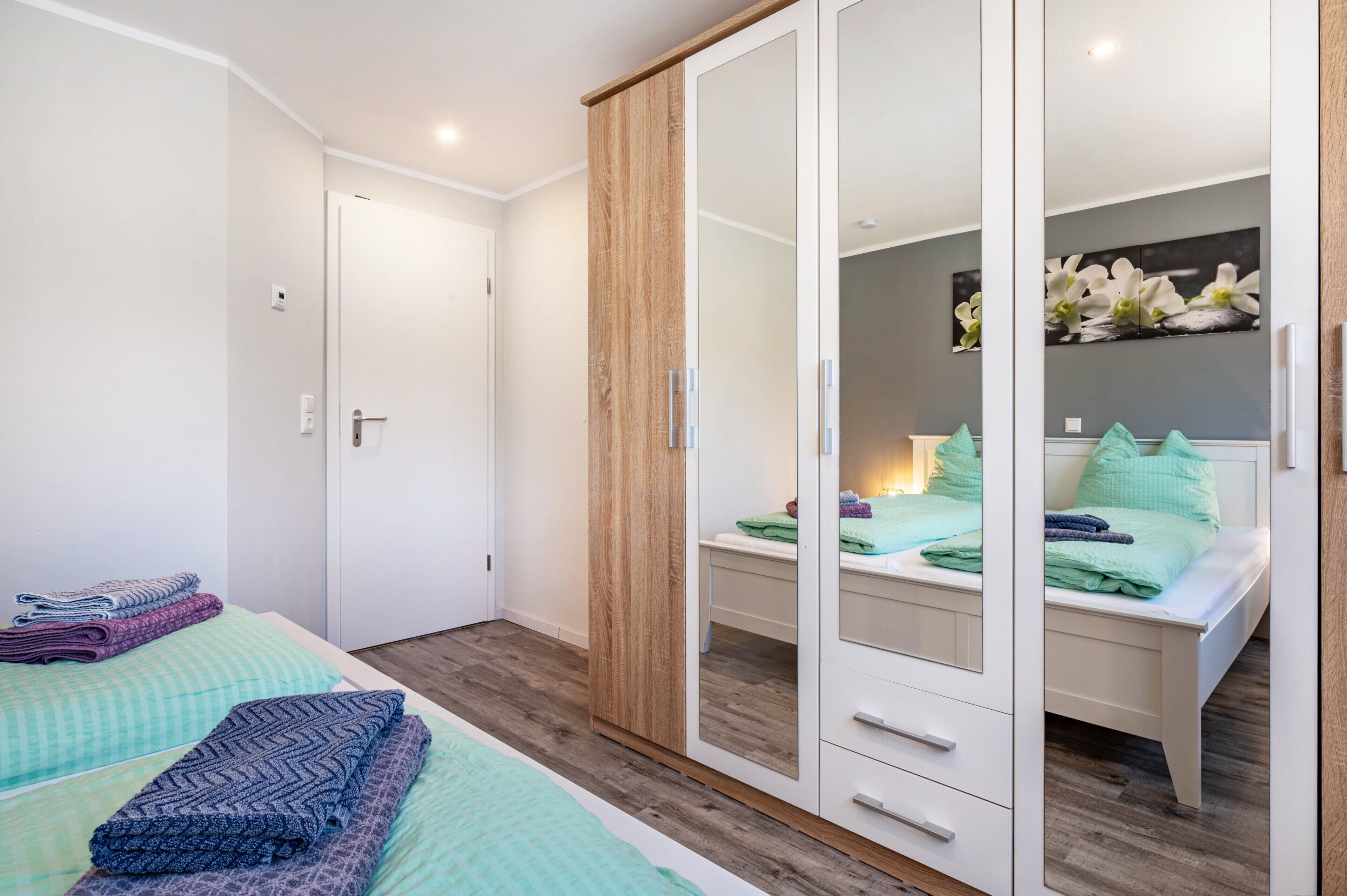 Une chambre à coucher avec un lit, une armoire et un bureau doté d’un miroir.