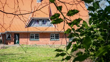 Een bakstenen gebouw met een rode dakbedekking, een groene deur en een klein raam.