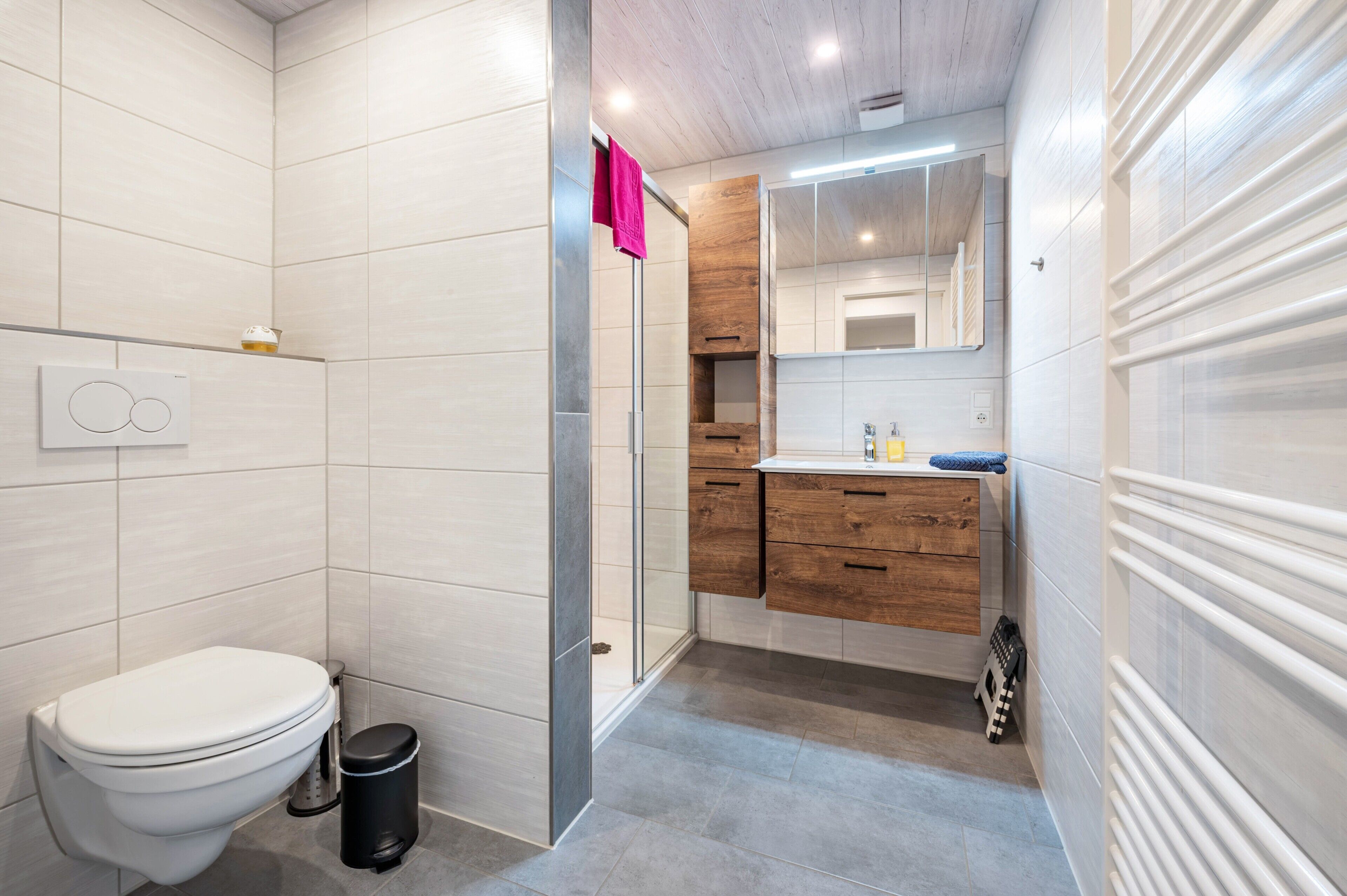 A modern bathroom with a toilet, shower, and vanity.