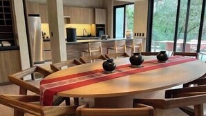 A modern dining area with a wooden table, chairs, and decorative vases. - Riverside Haven Elegant House with Serene Forest (Avandaro)