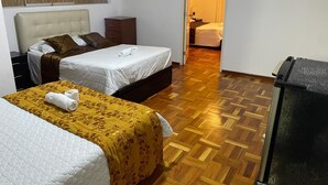 A hotel room with two beds, a wooden parquet floor, a wardrobe, and a television. - LIMA HOUSE MILANI (Lima)