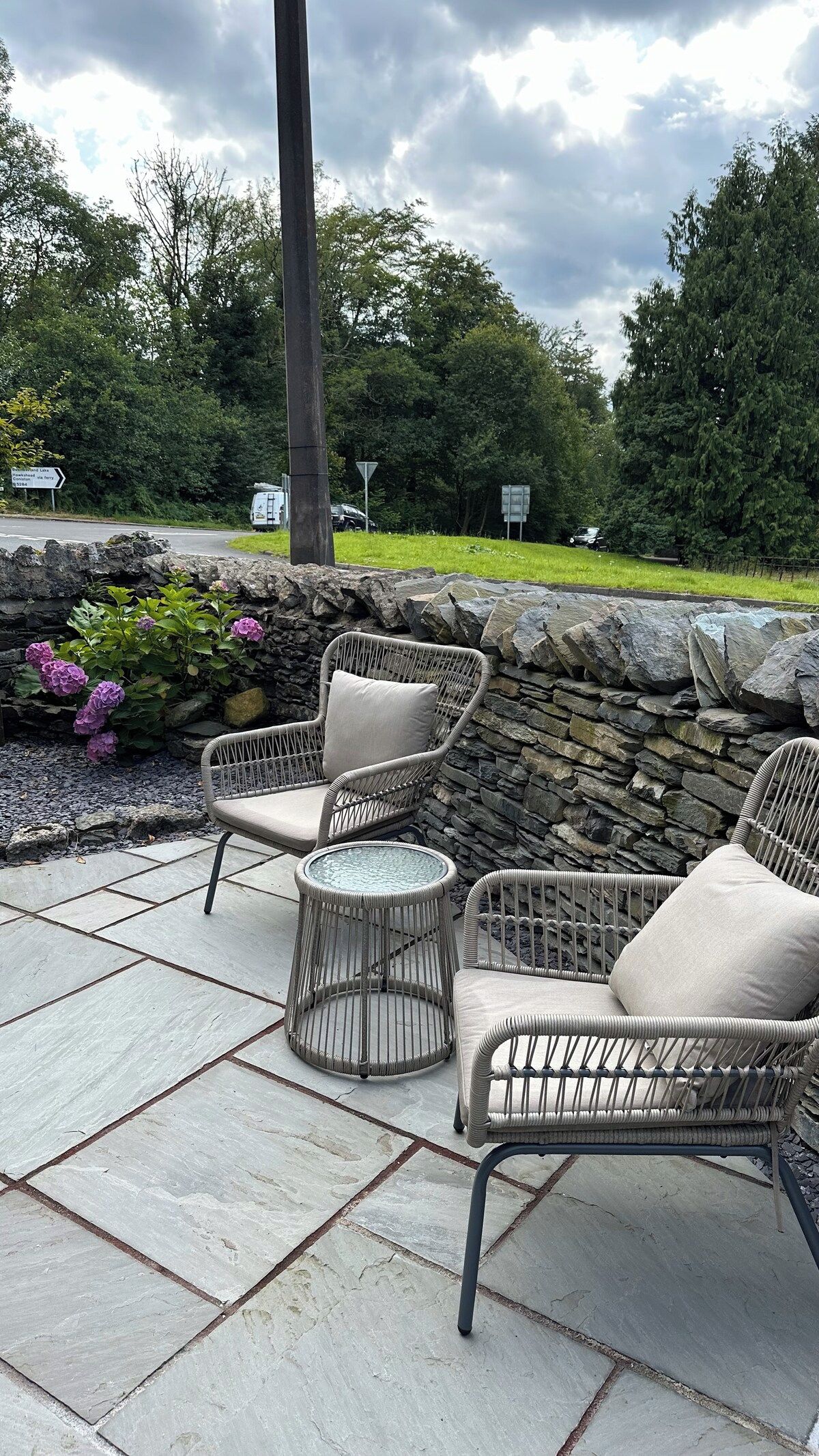 An outdoor patio area with wicker furniture and a stone wall.
