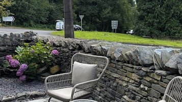 An outdoor patio area with wicker furniture and a stone wall.