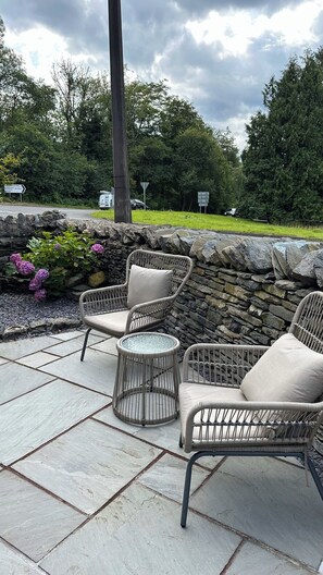 An outdoor patio area with wicker furniture and a stone wall.