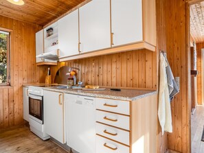 Eine kleine Küche mit Holzausstattung, einem eingebauten Ofen und einem Geschirrspüler.