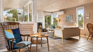 Una sala de estar acogedora con chimenea, muebles de madera y ventanas amplias.