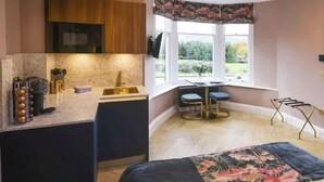 A compact kitchen with a built-in microwave, a sink, and a window with a view of greenery.