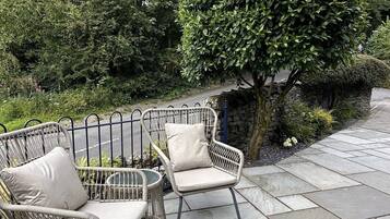 Un'area patio con due poltrone in vimini e un sentiero in pietra.