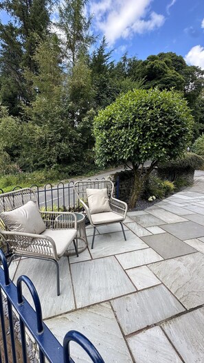 Un patio con dos sillas de mimbre y un sendero de piedra.