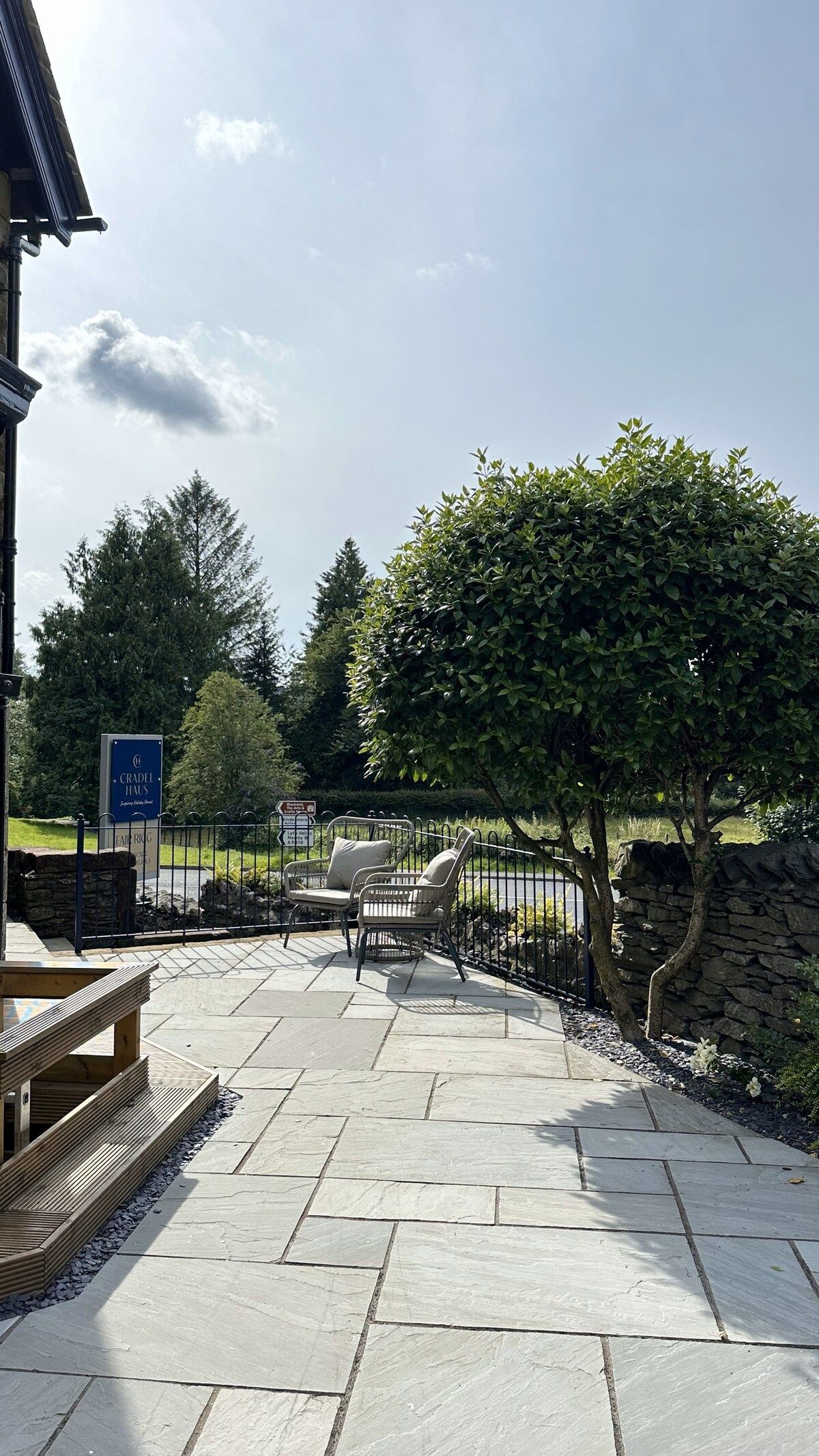 An outdoor patio area with stone flooring, a wooden bench, and a metal fence.