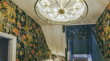 Experience unparalleled luxury in Windermere's hallway, captured in this photo showcasing stunning brass and glass light fittings, adding an extra touch of opulence and sophistication to the ambiance.