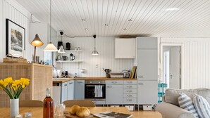 A modern kitchen with white cabinets, a wooden countertop, and a dining area with a table and chairs. - "Josef" - 1.4km from the sea by Interhome (Nykøbing Sj)