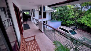 A balcony with a wooden bench, a car parked outside, and a view of greenery. - Oasis by Franklin Hotel Boutique (La Fortuna)