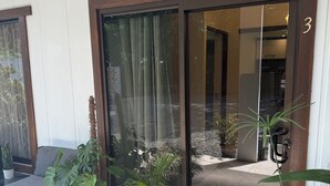 A hotel entrance with a glass door, a doormat with "HOME" written on it, and potted plants outside. - Oasis by Franklin Hotel Boutique (La Fortuna)
